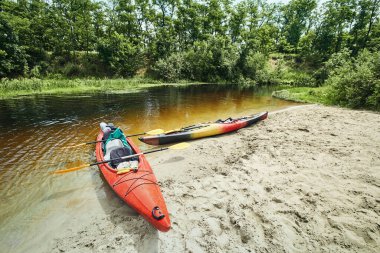 Bir grup genç kanoyla nehirde rafting yapıyor.