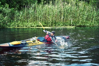 Bir grup genç kanoyla nehirde rafting yapıyor.