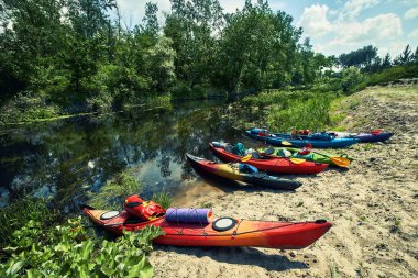 Bir grup genç kanoyla nehirde rafting yapıyor.