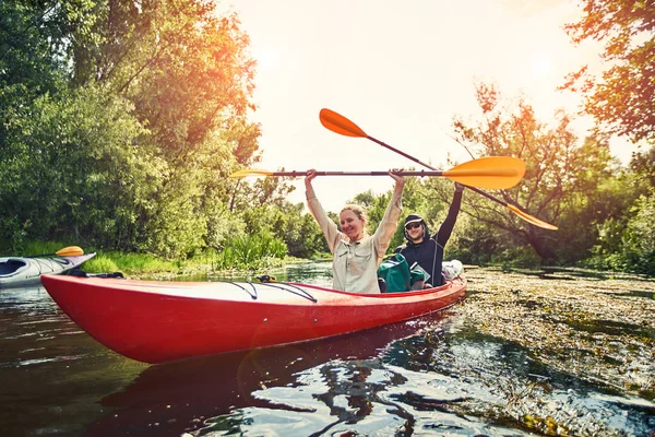 Bir grup genç kanoyla nehirde rafting yapıyor.