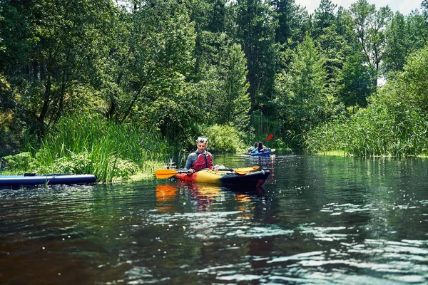 Bir grup genç kanoyla nehirde rafting yapıyor.