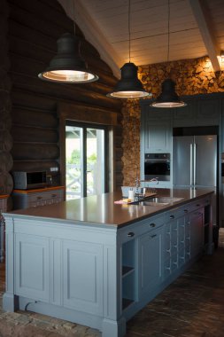 Mavi adalı taşra mutfağı, kolye ışıkları ve ahşap aksanlı..