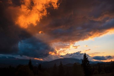 Parlak turuncu bulutlarla dolu dramatik bir gün batımı..