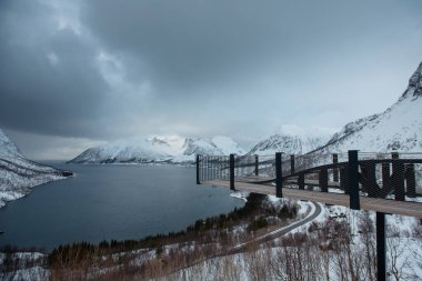 Fiyort üzerinde bir izleme platformu olan karlı dağ manzarası. Lofoten Adaları, Norveç
