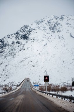 Karla kaplı dağ, bulutlu bir gökyüzünün altında ona doğru giden bir yol..