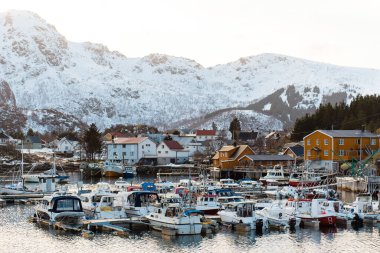 Limanda tekneleri olan karlı bir dağ köyünün manzarası. Lofoten Adaları, Norveç