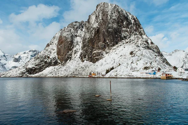 Mavi gökyüzünün altında sakin bir fiyort ile karla kaplı bir dağ. Lofoten Adaları, Norveç