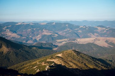 Yuvarlanan tepeleri ve berrak mavi gökyüzü olan manzaralı dağ manzarası.