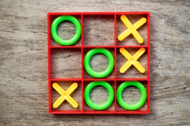 Tic Tac Toe masa oyunu yeşil O ve sarı ile kırmızı çerçeve ahşap arka plan üzerinde X