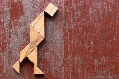 Şekil kırmızı eski ahşap arka plan üzerinde yürüyen adam içinde bulmaca Tangram