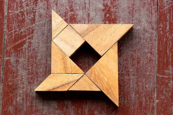 Kırmızı eski ahşap arka plan üzerinde shuriken şeklinde bulmaca Tangram