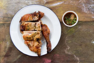 Kopya alanı ile ahşap arka plan üzerinde beyaz plaka ve sos ızgara tavuk Üstten Görünüm