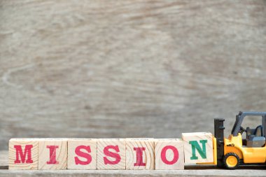 Oyuncak forklift tutun ahşap arka plan üzerinde kelime misyonu tamamlamak için mektup blok N