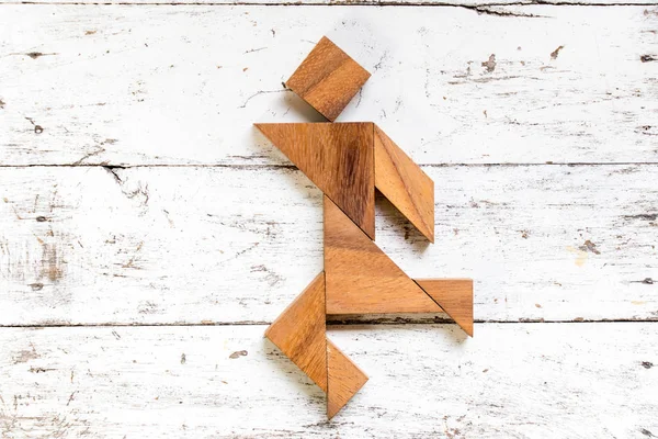 Eski Beyaz ahşap zemin üzerinde mutlu çalışan adam şeklinde bulmaca Tangram