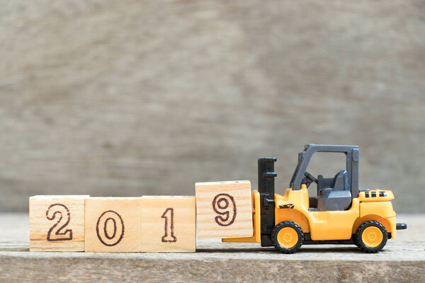 Игрушечная форточка держит букву 9, чтобы закончить слово 2019 на деревянном фоне
