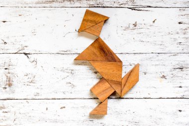 Eski Beyaz ahşap zemin üzerinde mutlu çalışan adam şeklinde bulmaca Tangram