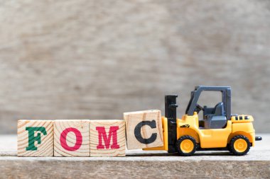 Toy forklift hold letter block c in word FOMC (abbreviation of Federal Open Market Committee) on wood background clipart