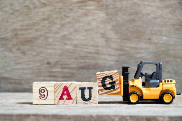 Tam sözcük 9 Ağustos ahşap arka plan üzerinde oyuncak forklift tutun bloğuna G (kavramı için takvim tarihi ay Ağustos)