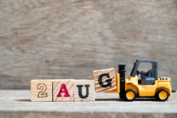 Ahşap arka plan üzerinde tam Word'e 2 Ağustos oyuncak forklift tutun blok G (kavramı için takvim tarihi ay Ağustos)
