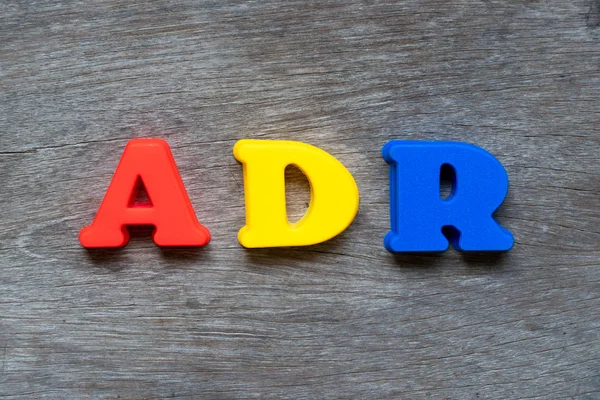 Word Adr (ters ilaç reaksiyonu kısaltma) ahşap arka plan üzerinde renkli plastik alfabesi
