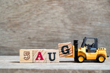 Oyuncak forklift tutun blok G tam word 5 Ağustos ahşap arka plan üzerinde (kavramı için takvim tarihi ay Ağustos)