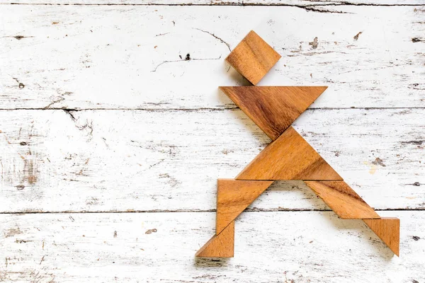 Eski Beyaz ahşap zemin üzerinde mutlu çalışan adam şeklinde bulmaca Tangram