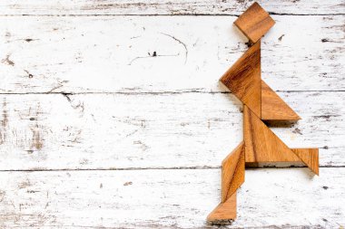 Eski Beyaz ahşap zemin üzerinde mutlu çalışan adam şeklinde bulmaca Tangram