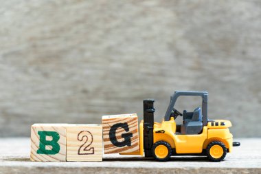 Oyuncak forklift ahşap arka plan üzerinde mektup sözcük B2g G bloğunda (kısaltma iş hükümet için) tutun