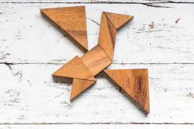 Eski Beyaz ahşap arka plan üzerinde kuş şekli uçan bulmaca Tangram