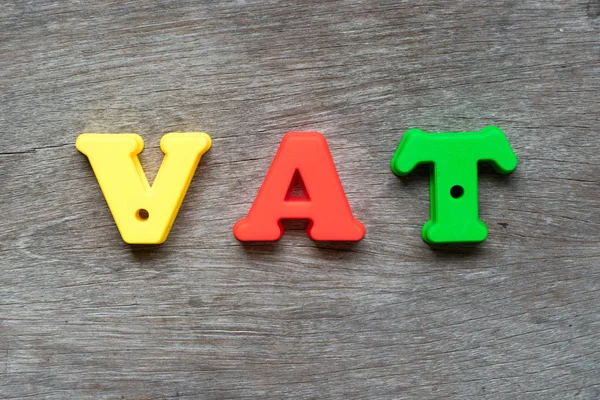 Colorful plastic alphabet in word VAT (Abbreviation of value added tax) on wood background