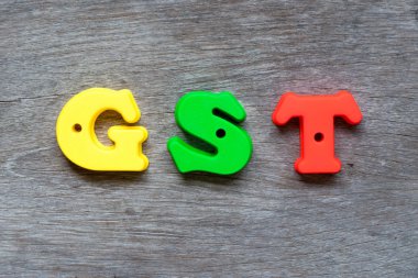 Word Gst (kısaltma mal ve hizmet vergisi) ahşap arka plan üzerinde renkli plastik alfabesi