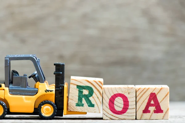 Oyuncak forklift tutun mektup blok içinde kelime Roa (varlıkların getirisi kısaltma) ahşap arka plan üzerinde