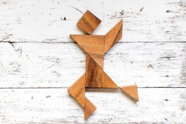 Tangram bulmacanın mutlu çalışan veya adam şekil eski beyaz ahşap arka plan üzerinde dans