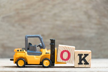 Oyuncak forklift tutun mektup blok o kelime Tamam ahşap arka plan üzerinde