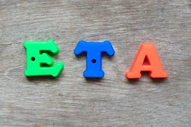 Word (kısaltma, tahmini zaman, varış) ahşap arka plan üzerinde renkli plastik alfabesi