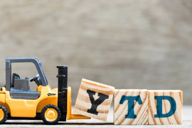 Oyuncak forklift Word Ytd (yıl başından bugüne kısaltma) ahşap zemin üzerine mektup blok Y tutun