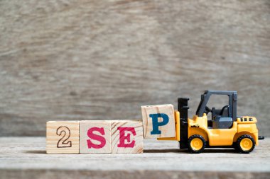 Ahşap arka plan (takvim tarihi Eylül ayında konsepti üzerinde kelime 2 Eylül tamamlamak için oyuncak forklift tutun blok P)