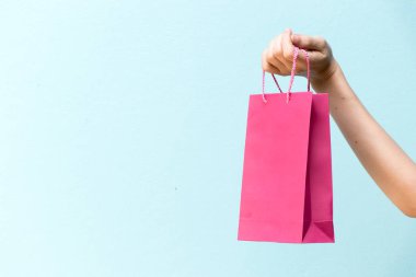 İş kadını elini tut pembe alışveriş çantası mavi beton zemin üzerine