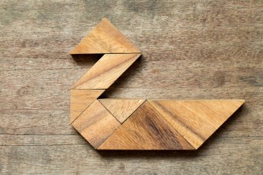 Ahşap arka plan üzerinde kuğu şeklinde bulmaca Tangram