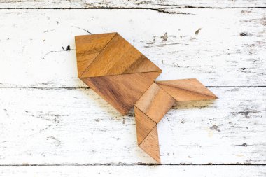 Tangram bulmacanın eski beyaz ahşap arka planda (Konsept yeni keşif veya iş, başlangıç için roket veya füze şeklinde)