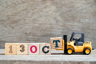 Ahşap arka plan (takvim tarihi Ekim ayında konsepti üzerinde 13 Ekim kelime tamamlamak için oyuncak forklift tutun blok T)