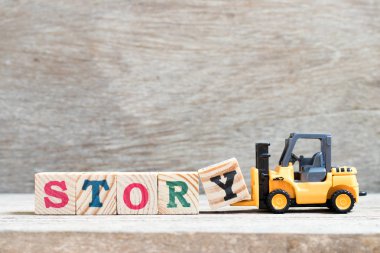 Oyuncak forklift kelime hikaye ahşap arka plan üzerinde tamamlamak için mektup blok y tutun