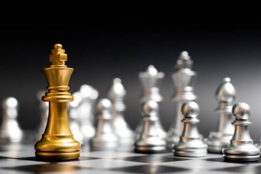 Altın Kral satranç parça siyah arka plan (Konsept şirket stratejisi, iş zafer veya karar için başka bir gümüş takım ile yüz)