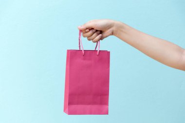 İş kadını elini tut pembe alışveriş çantası mavi beton zemin üzerine