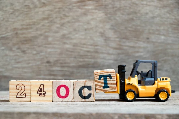 Ahşap arka plan (takvim tarihi Ekim ayında konsepti üzerinde 24 Ekim kelime tamamlamak için oyuncak forklift tutun blok T)