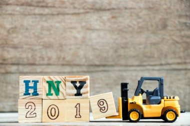 Oyuncak sarı forklift tutun mektup blok 9 tam word Hny 2019 (kısaltma mutlu yeni yıl) için ahşap arka plan üzerinde