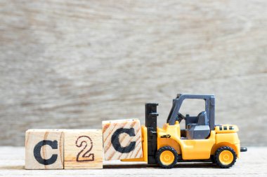 Word c2c tamamlamak için oyuncak forklift tutun harfi C blok (tüketiciye tüketici kısaltma) ahşap arka plan üzerinde