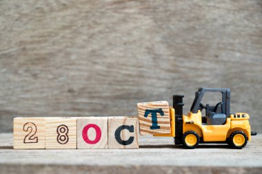 Ahşap arka plan (takvim tarihi Ekim ayında konsepti üzerinde 28 Ekim kelime tamamlamak için oyuncak forklift tutun blok T)