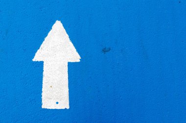 İleri yönde ok simgesi mavi beton yol arka plan üzerinde beyaz resim
