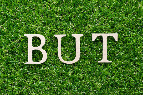 Деревянный алфавит в словах, но на искусственном зеленом фоне травы
